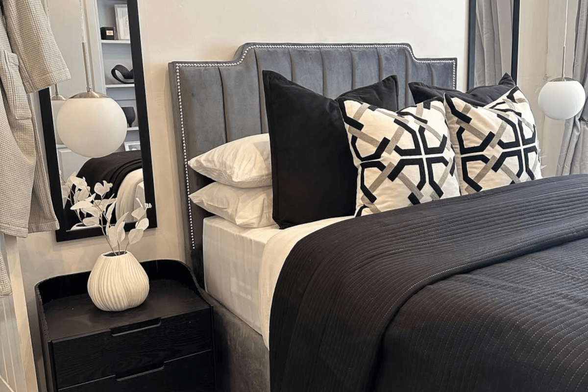 Stylish monochrome bedroom with crisp white bedding, black accent cushions, and a minimalist black headboard.