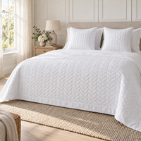 Hampton & Astley white leaf-quilted cotton throw and cushions styled on a bed
