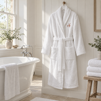 Hampton & Astley white towelling dressing gown hanging in a bathroom